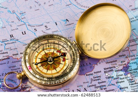 A brass compass laid on a map of Russia