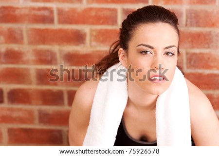 a young female in gym wear  on a brick background