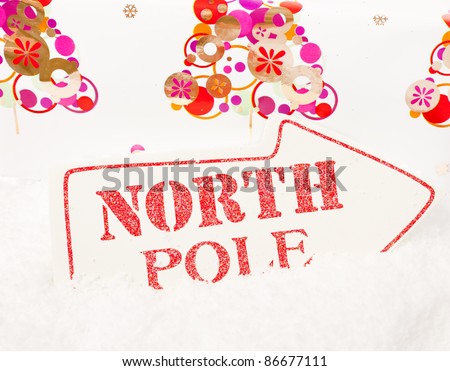 A white sign showing the way to the north pole sat in snow