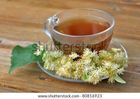 Linden tea on a wooden table. Tea with linden flowers. Cup of tea on the table. Brewed lime beverage. Medicinal tea.