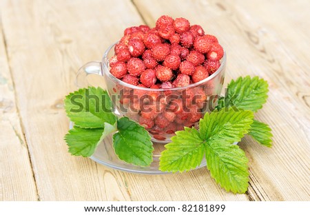 Ripe wild berry. Strawberries in a glass bowl. A cup of strawberries with a wooden table in the background.