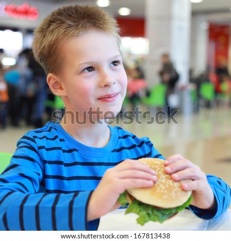 handsome little boy eating burger