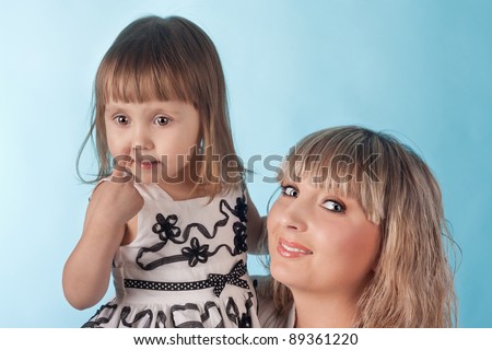 cute little girl showing to her nose sitting near her young beautiful mother