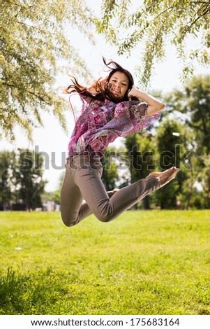 Happy young woman jumping in park and having fun.