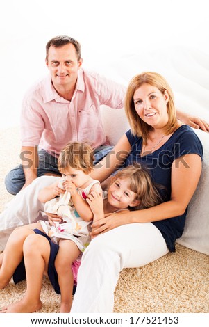 Beautiful happy family sitting on the carpet.