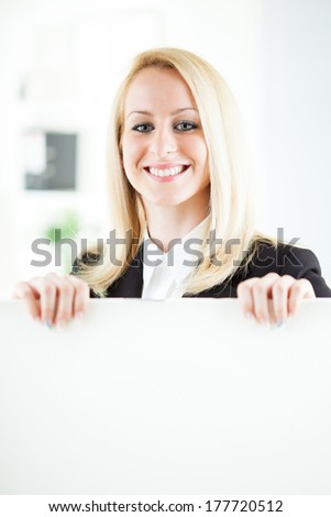 Beautiful young businesswoman holding Blank business board in the office. Looking at camera. Selective Focus.