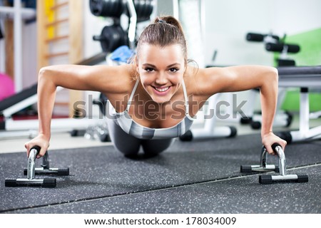 Cute Young girl doing push-ups in gym. Front View.