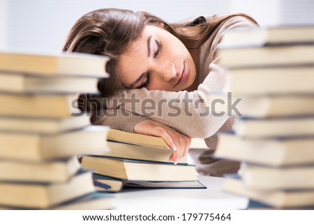 Tired student fell a sleep between many books, while learning. Selective focus.