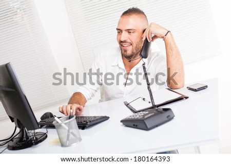Attractive businessman sitting at the table and talking on the telephone