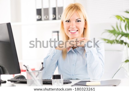 Businesswoman in the office. Sitting at the table with computer and Looking at camera.