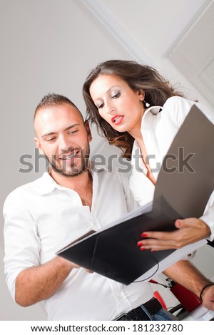 Business man and business woman looking in folder and talking about business project