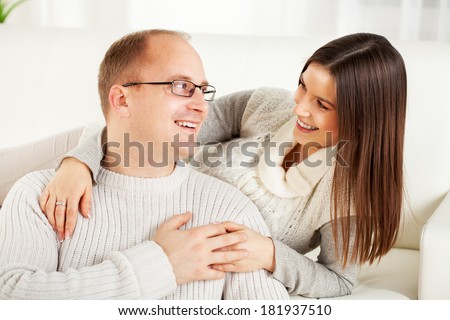 Happy beautiful Young couple sitting and hugging in home interior. Looking at camera.