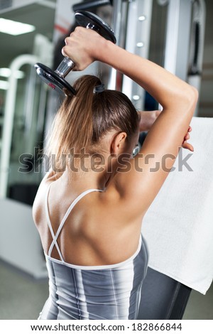 Cute Sporty young woman doing exercise in a fitness center. She is working exercises to strengthen her triceps.