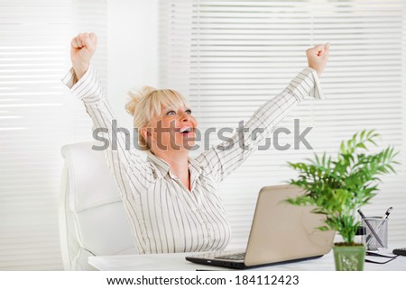 Cheerful Business woman sitting in the office with raising hands