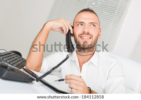 Attractive businessman sitting at the table and talking on the telephone.