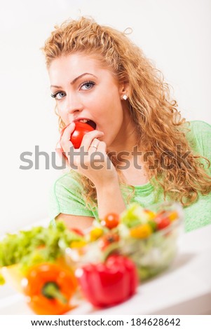 Beautiful young woman eating tomato