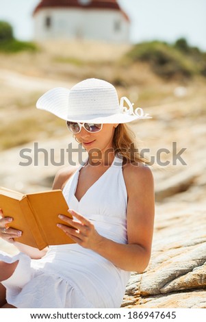 Beautiful Girl with a book sitting on the rock and Expressing Positivity.