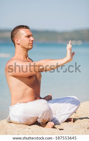 Young man meditating on the beach.