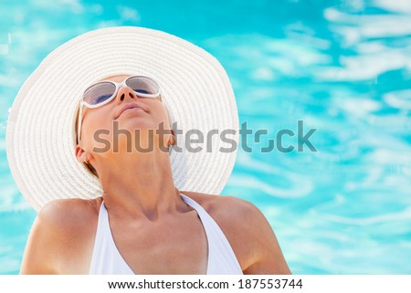 Portrait of young beautiful woman enjoying the sun by the pool.