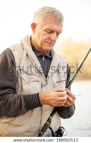 Senior Fisherman hooks a worm on a fishing hook.