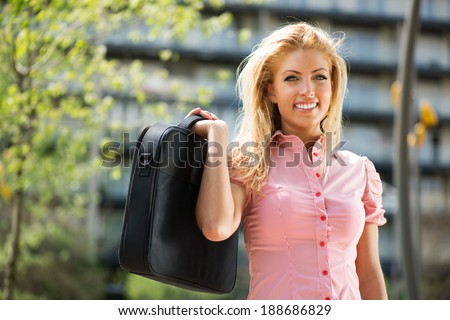 Portrait of Beautiful Smiling woman in the park with business bag in shes hand.