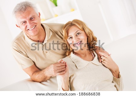 Hugging Senior couple in living room.
