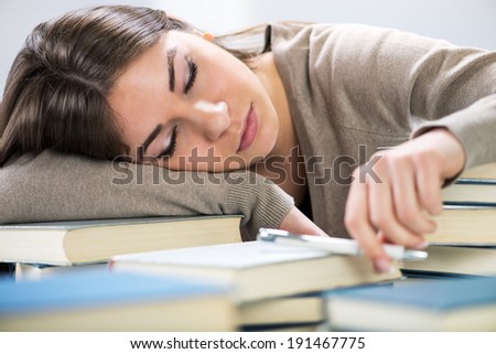 Tired student fell a sleep between many books, while learning.