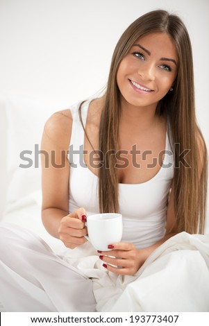 Cute young beautiful woman drinking coffee in the bed