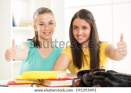 Two Happy beautiful female students learning and showing thumbs up