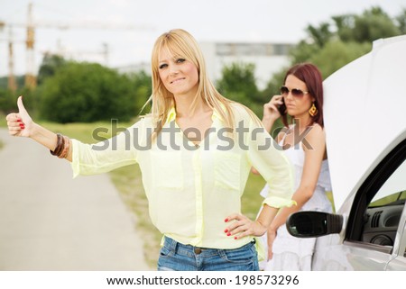 Two Young tourist women Hitchhiking on the road and waiting for help because of Car troubles.