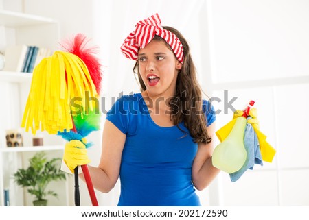 Portrait of a young beautiful unhappy maid holding a cleaning equipment.