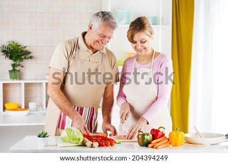 Happy Senior Couple cutting meat in the kitchen