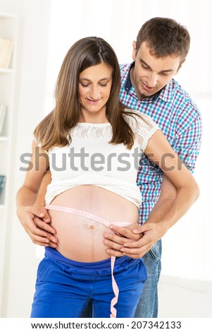 Happy couple measuring on pregnant woman\'s belly