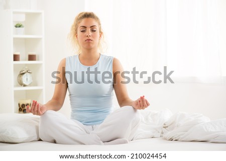 Cute young beautiful girl at morning doing yoga on the bed