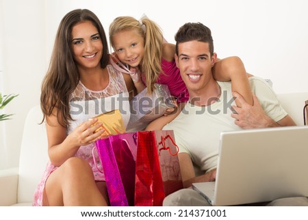Beautiful happy family sitting at home with laptop and shopping bags.