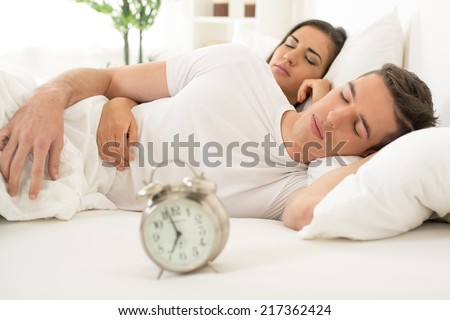 Young hugging couple sleeping on the bed in bedroom