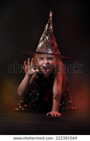 Little halloween witch in dark clothing with evil face.