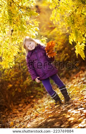 Cute Little girl in the park posing with yellow leaves