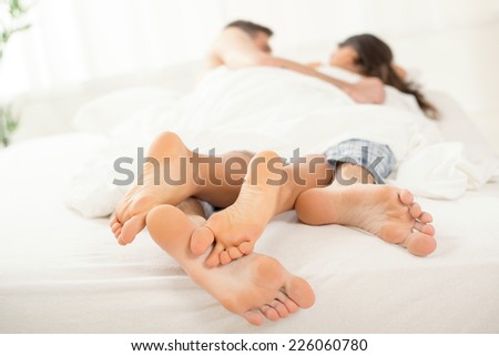 The feet of a young heterosexual couple relaxing in bed. Selective Focus, focus on the legs.