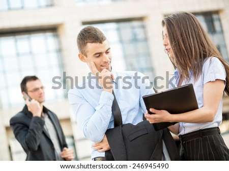 Young businessman talking to his pretty business partner in front of office building.