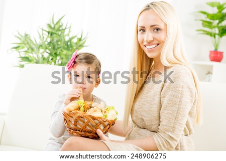 Beautiful smiling mother gives a wicker basket with fresh pastries her daughter, who gladly eat mom\'s pastry.