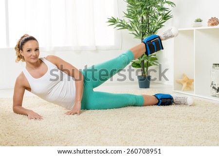 Beautiful young woman exercising with dumbbells at home.