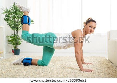 Beautiful young woman exercising with dumbbells at home.