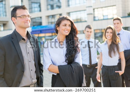 Young and handsome businessman and businesswoman standing with his team front of office building and smiling.