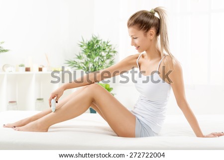 Young beautiful woman depilation leg with Electric Razor.