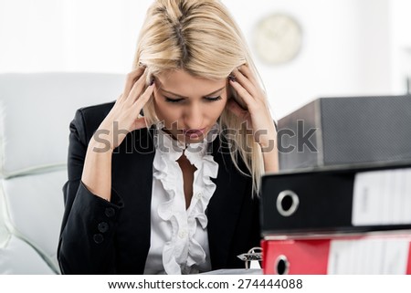 Young tired businesswoman worried sitting in the office. In front of her is a bunch of binders.