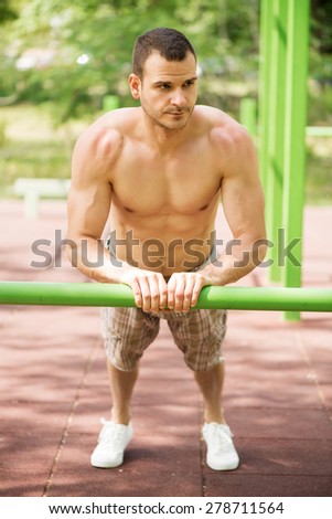 Young muscle Man doing vertical push-ups in the park.