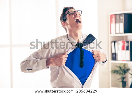 Angry businessman ripping open his shirt and exposing a Superhero red costume underneath. The man is wearing glasses.