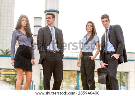 Group of young successful business people standing in front of office building dressed in suits.