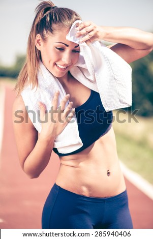 Beautiful young slim woman resting after training and wipes the sweat with towel.